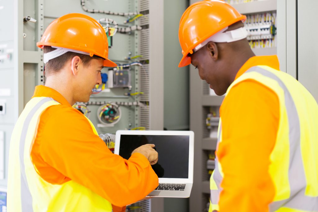 men with hard hats in mechanical room on laptop