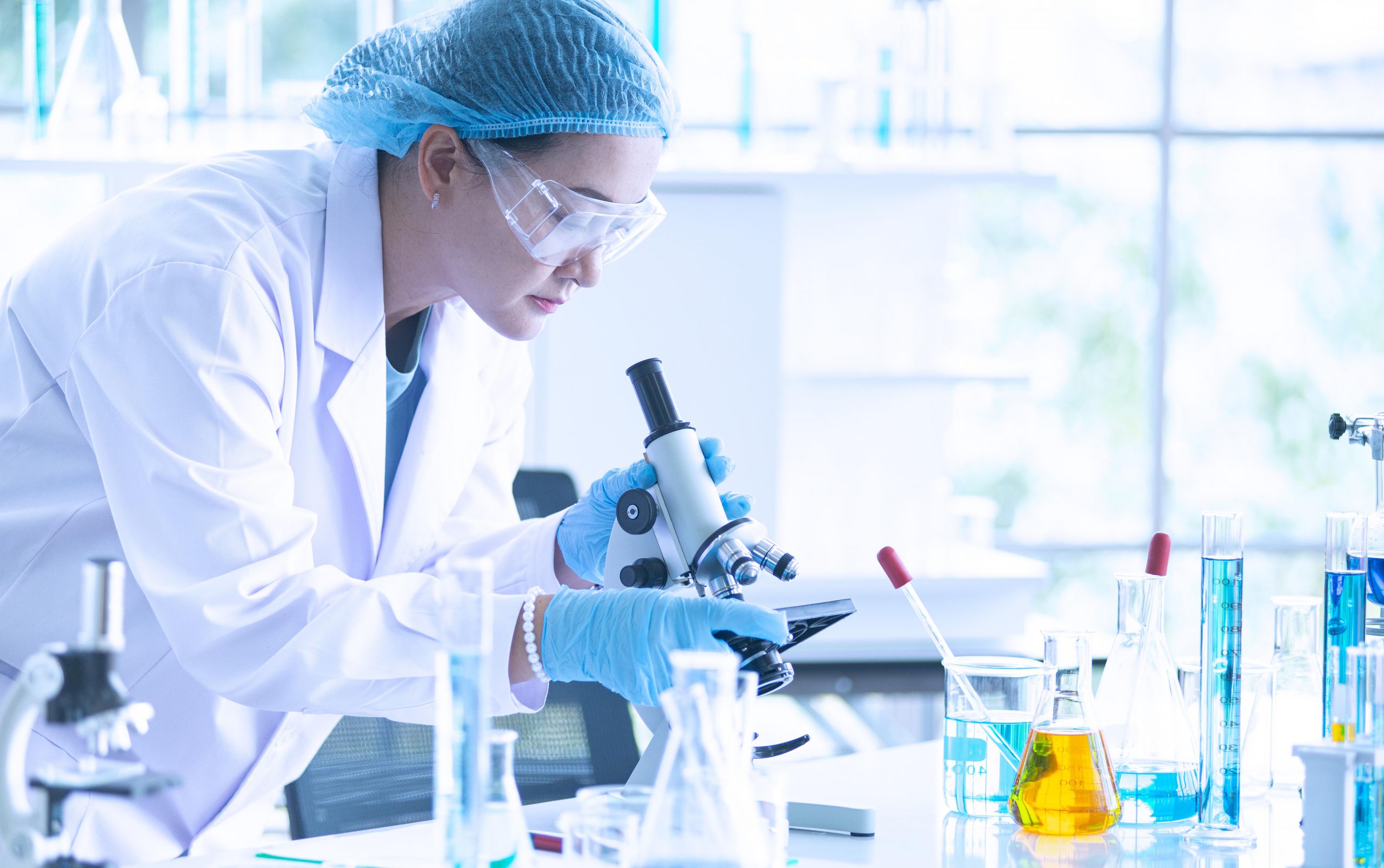 woman in lab coat looking in microscope