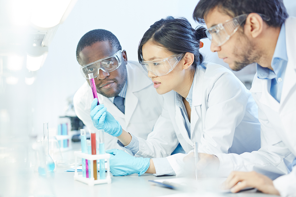 people in lab coats viewing test tubes